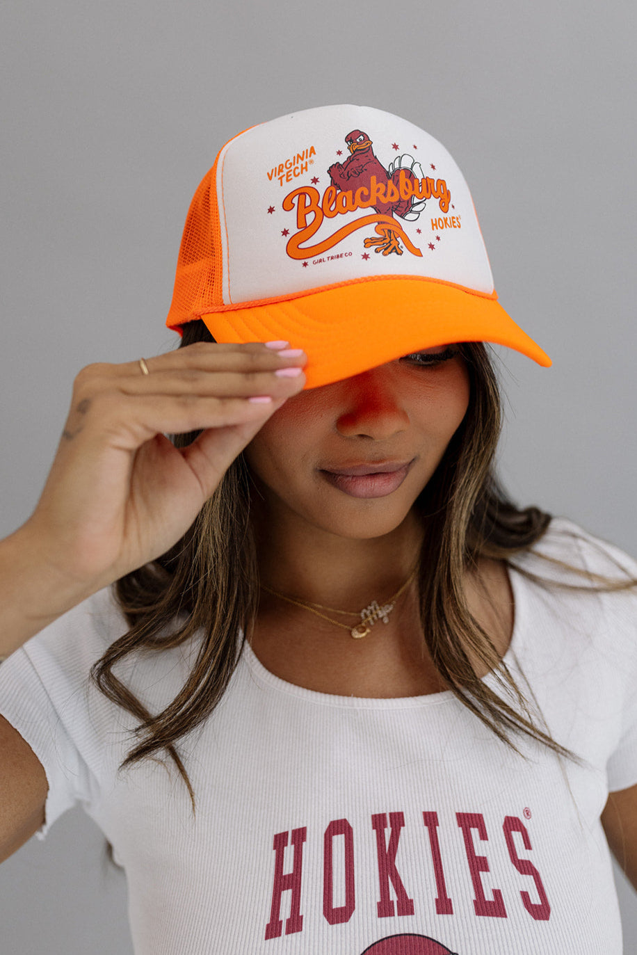 Show off your school spirit with the Virginia Tech: Blacksburg Trucker Hat! This stylish womens hat features the iconic Virginia Tech logo and is perfect for any avid fan. Stay cool and look cool with this trucker hat, the perfect addition to any game day outfit. Go Hokies!

Hat Brand: Otto

Color:&nbsp;White and Neon Orange

Girl Tribe Co. proudly&nbsp;designs, prints, embroiders,&nbsp;and&nbsp;ships&nbsp;all of our graphics in the Girl Tribe production facility in Charlotte, NC.&nbsp;