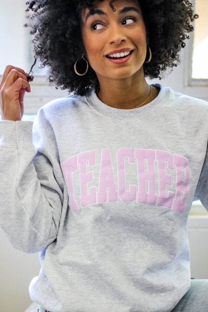 Gray crewneck sweatshirt with TEACHER in light pink block letters 